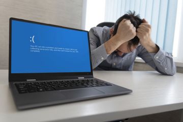 showing error blue screen on the Laptop against the background of an angry upset man clutching his head